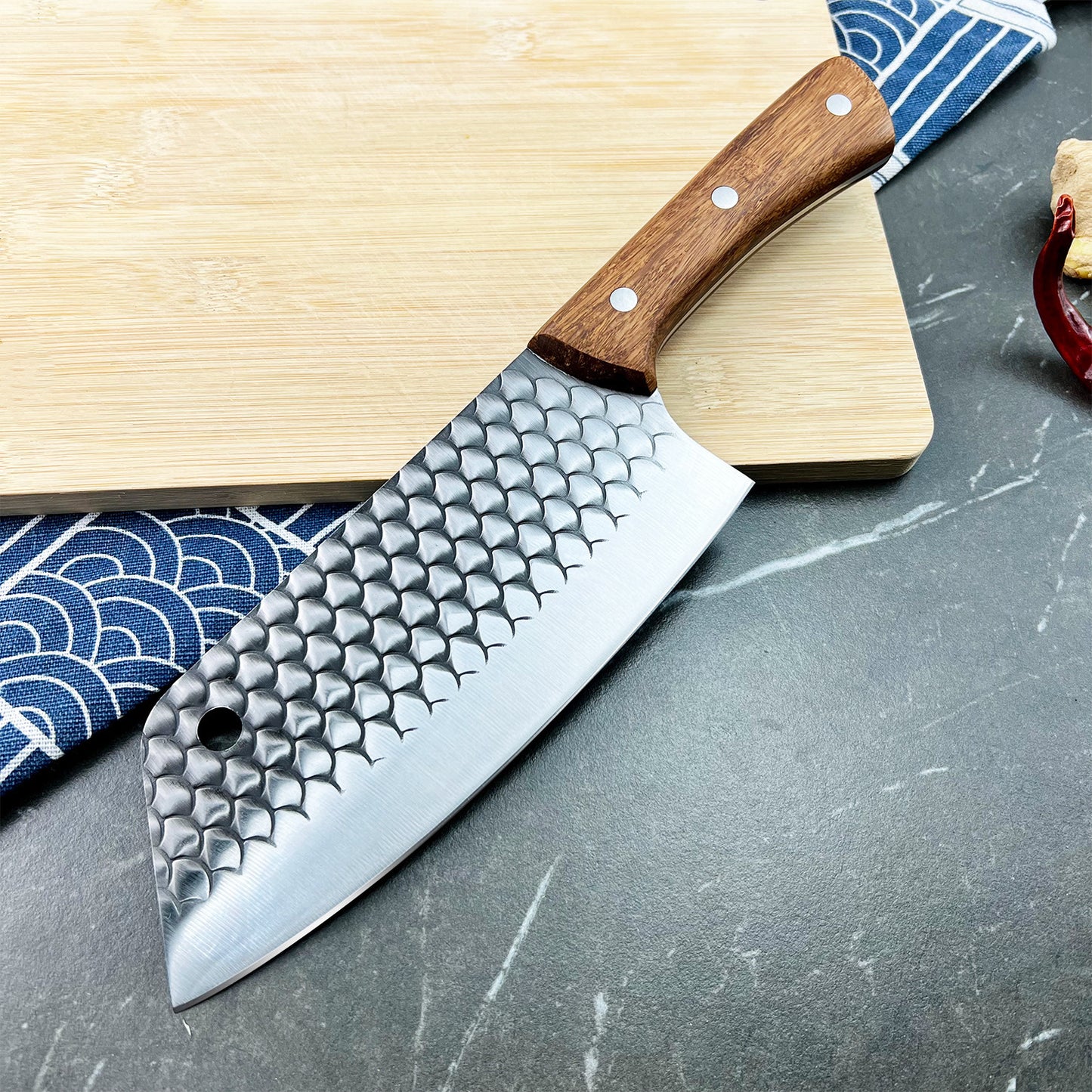 Kamagata knife with textured blade on a wooden cutting board