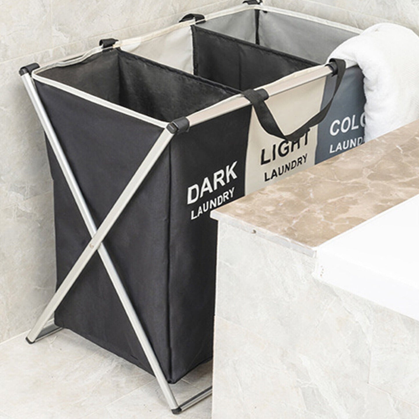 Black laundry basket with labels for dark and light laundry on a marble surface.