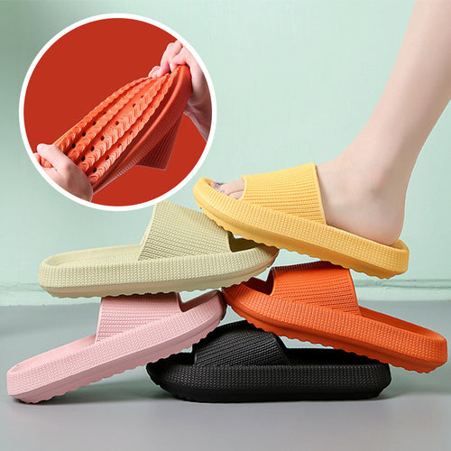 A stack of various colored slippers, with one slipper lifted to show the non-slip sole.