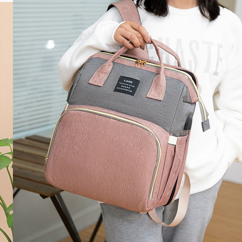 Person holding a pink and gray backpack with a visible brand label.