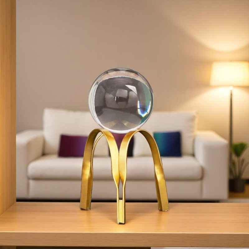 Decorative object with a reflective sphere on a gold stand in a living room setting