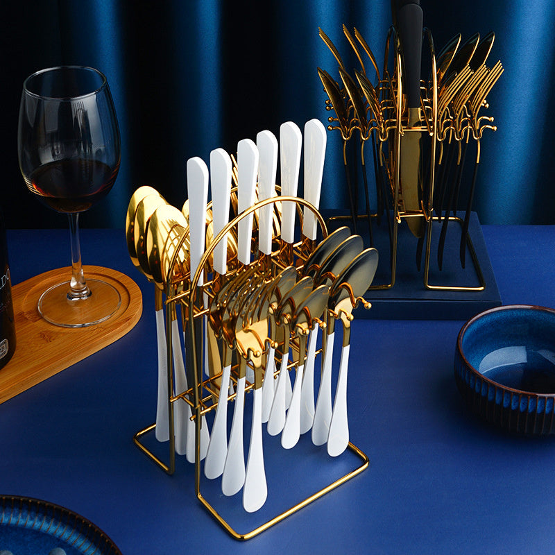 Gold and white cutlery set on a blue surface with a glass of red wine.