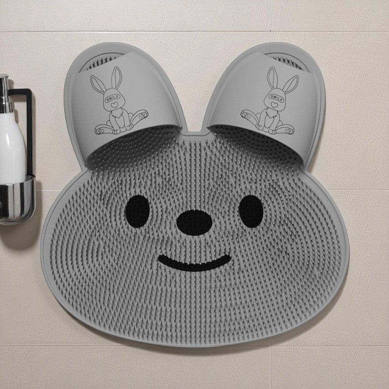 Gray bath mat with bunny ears and face on a tiled bathroom floor.