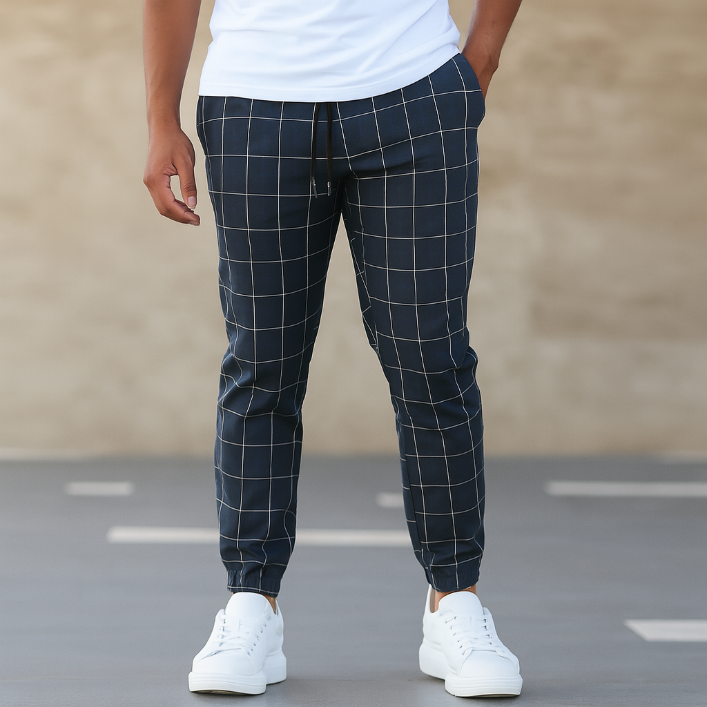 Person wearing navy checkered pants and white sneakers on a plain background