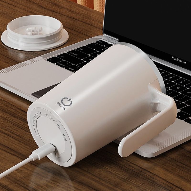 White mug with power symbol on a wooden desk next to a laptop
