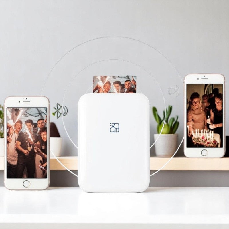 White electronic device on a white surface with two smartphones displaying photos of people.
