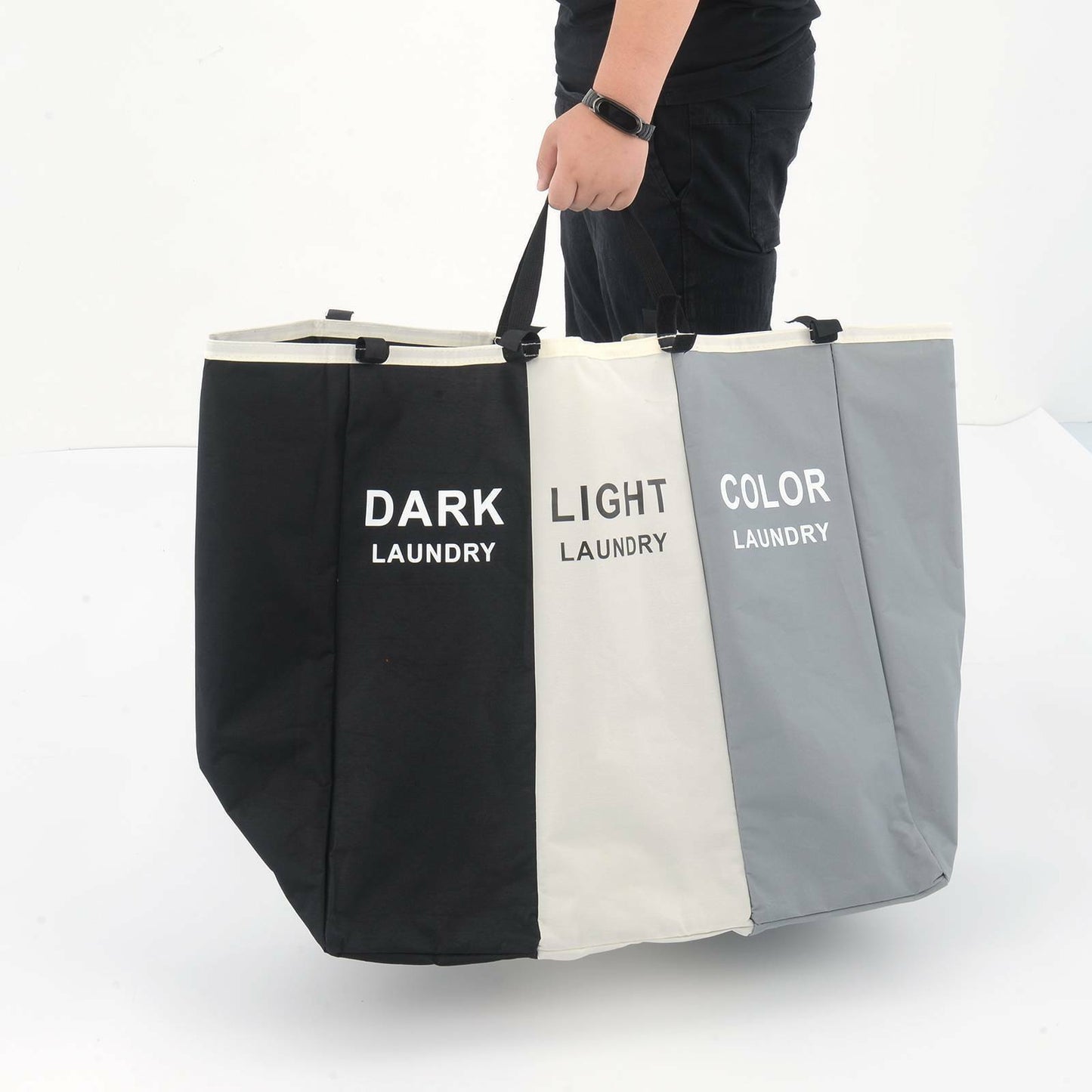 Three-section laundry bag labeled 'Dark Laundry', 'Light Laundry', and 'Color Laundry' held by a person.