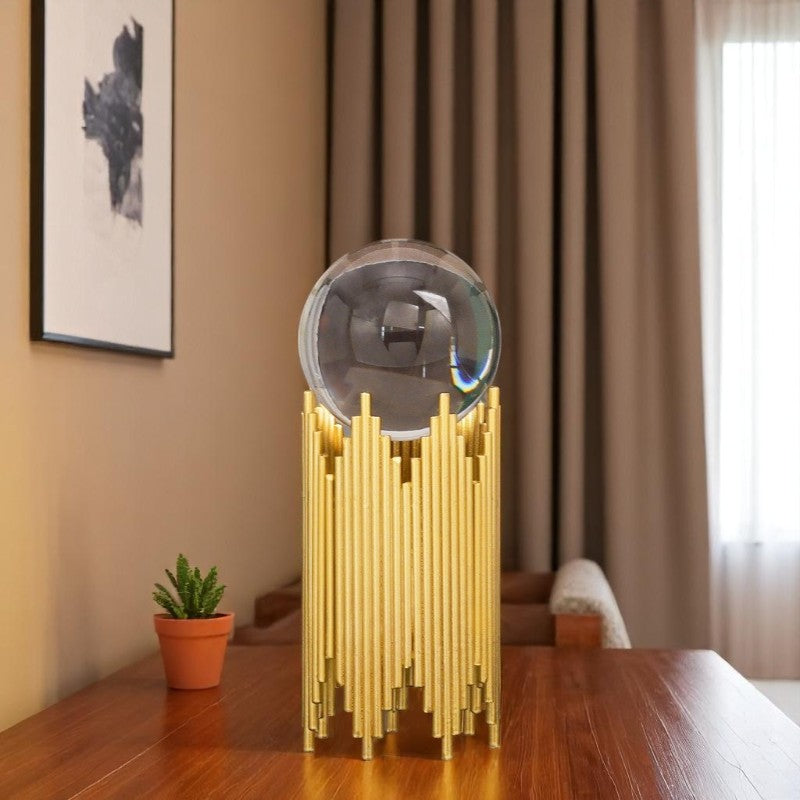 Decorative table lamp with gold base and silver shade on a wooden table.