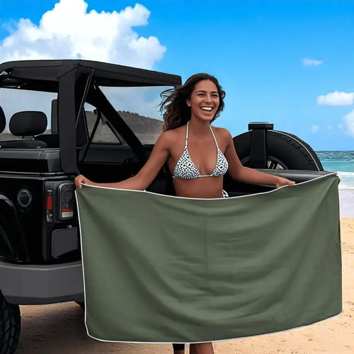 Woman holding a green towel by a jeep on a beach