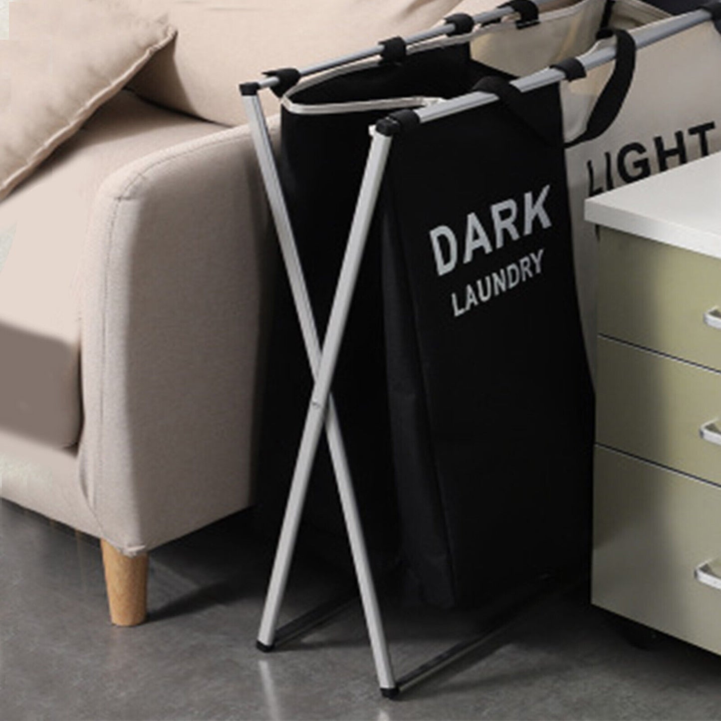 Black laundry bag labeled 'Dark Laundry' on a stand in a living room.