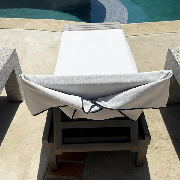White cushioned lounge chair on a concrete platform by a pool