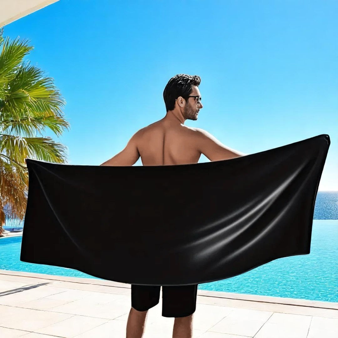 Man holding a black towel by a pool with palm trees and blue sky in the background