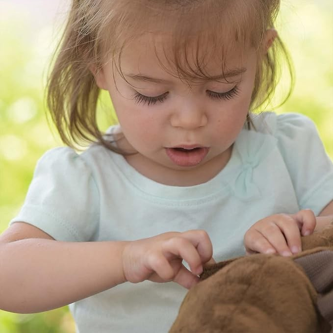 Child playing with a brown teddy bear outdoors