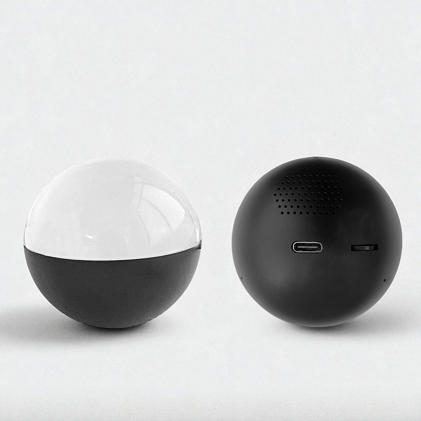 Two spherical video player ball, one black and one with a transparent top, on a light gray background.