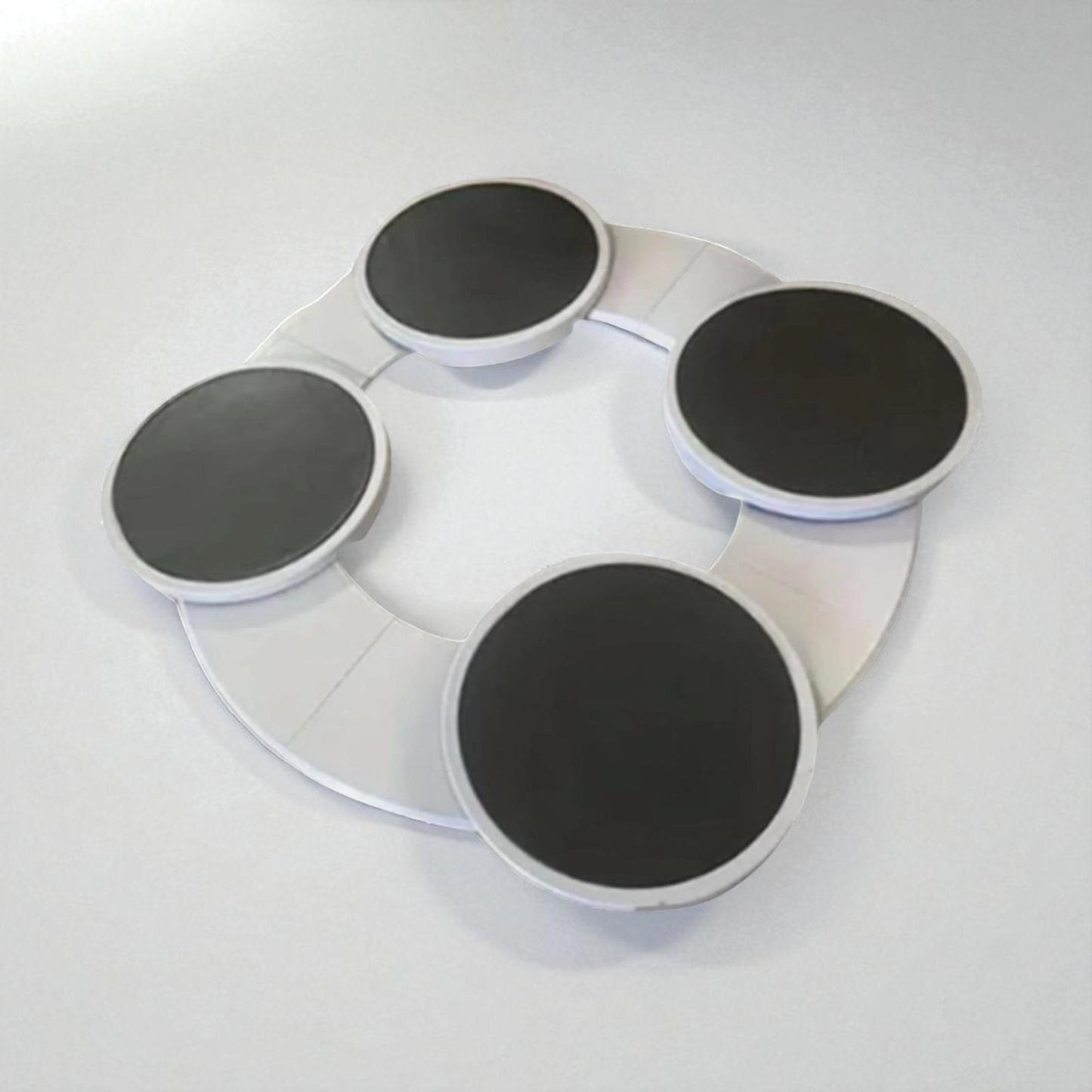 Round white tray with four black circular pads on a light gray background