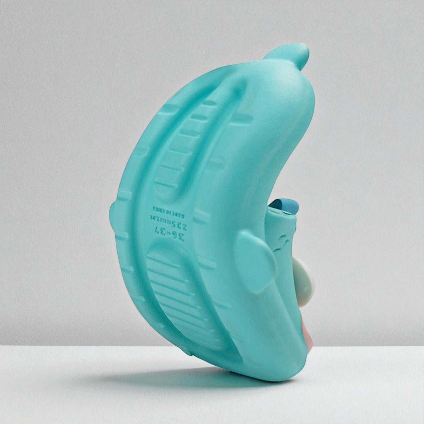 Turquoise rubber duck on a white surface with a light gray background