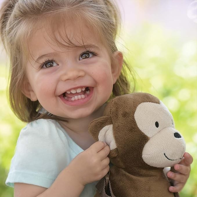 Child holding a monkey plush toy with a blurred green background