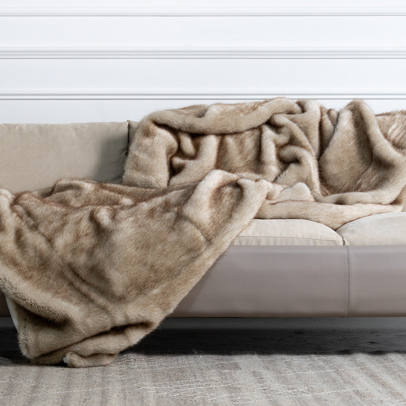 Beige blanket draped over a beige sofa against a white wall.