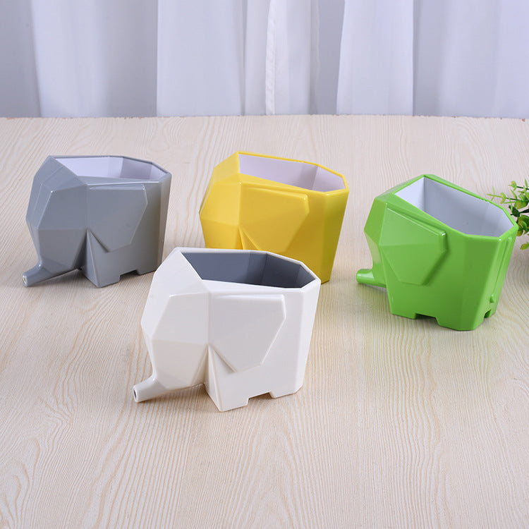 Four elephant-shaped planters in gray, yellow, white, and green on a light wooden surface.