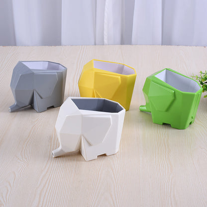 Four elephant-shaped planters in gray, yellow, white, and green on a light wooden surface.