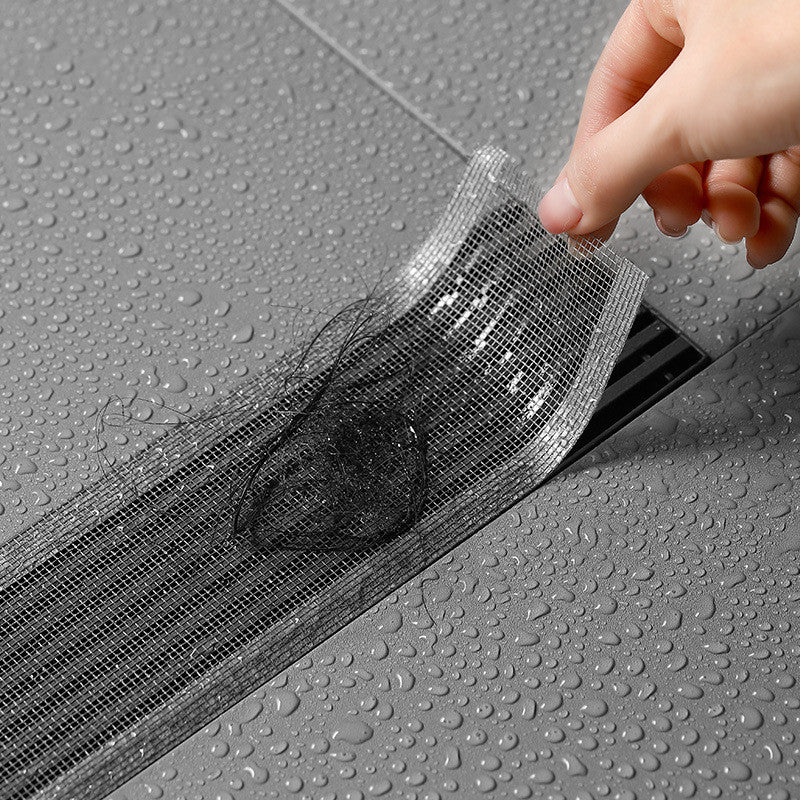 Person applying a black mesh strip to a gray surface with water droplets.