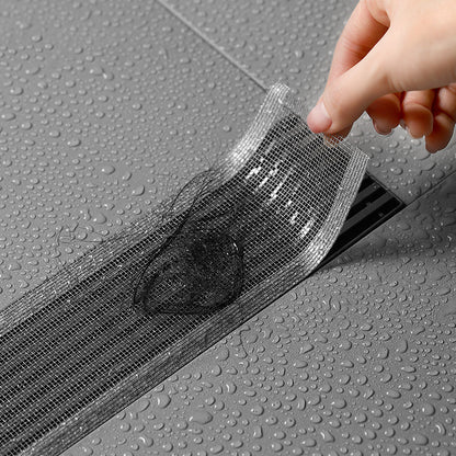 Person applying a black mesh strip to a gray surface with water droplets.