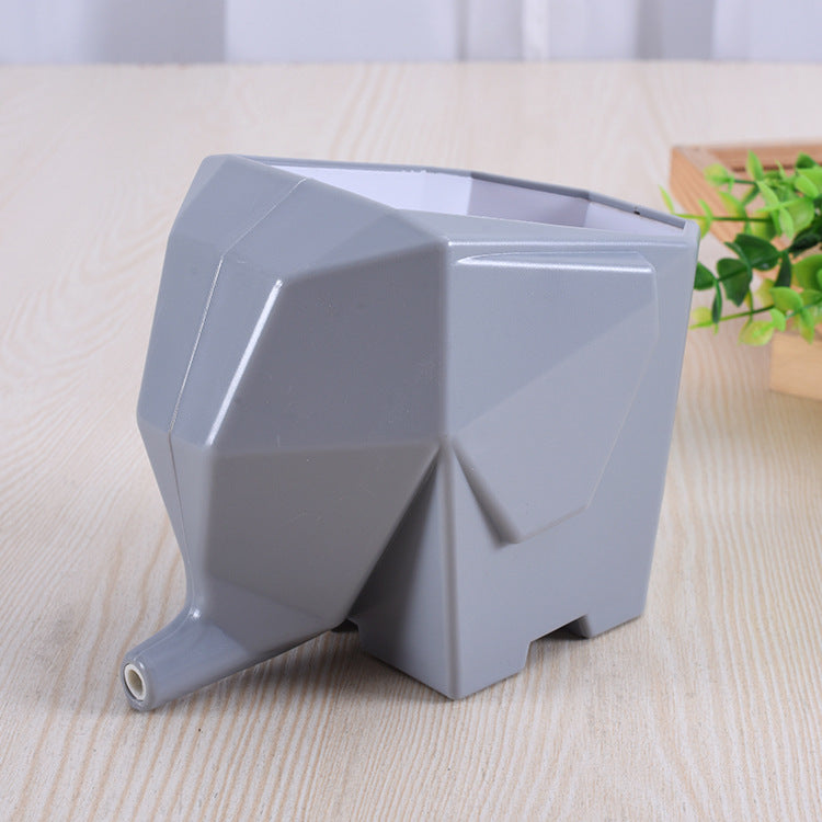 Gray elephant-shaped planter on a wooden surface with a plant in the background
