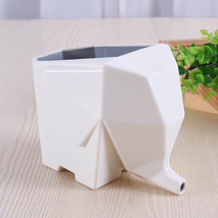 White elephant-shaped planter on a wooden surface with a blurred background