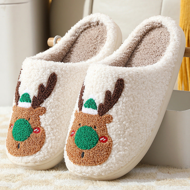 Pair of white slippers with reindeer face designs on a light background