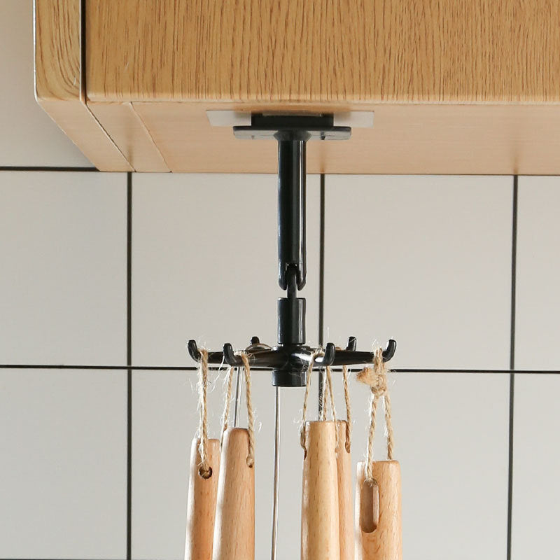 Wooden utensils hanging from a black hook against a tiled wall.
