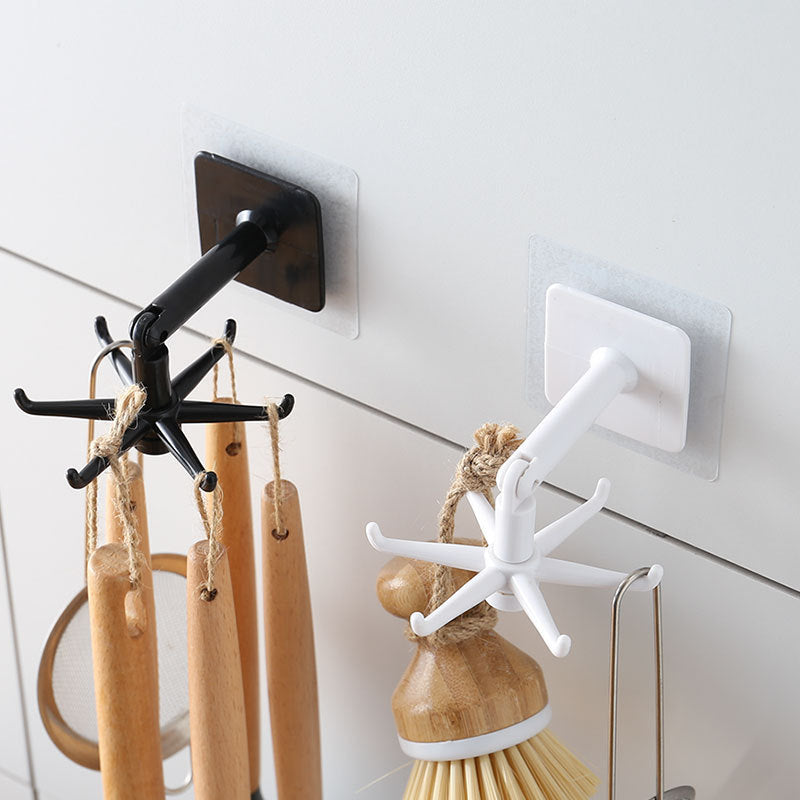 Black and white wall hooks with wooden utensils on a white wall.