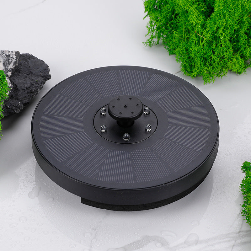 Black circular device on a light gray surface with green plants around