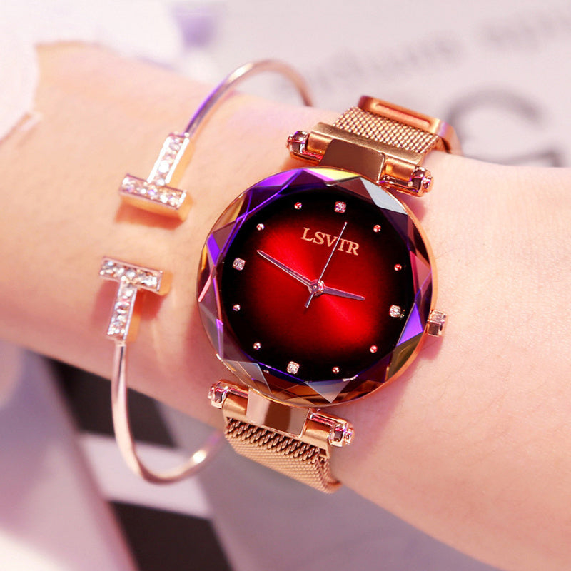A woman's watch with a rose gold metal band and case, featuring a multicolored glass dial and a spiral crown.