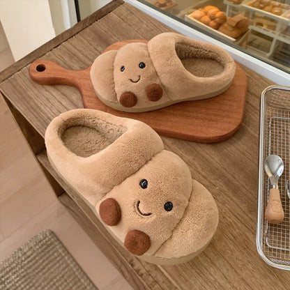 Pair of cute animal-shaped slippers on a wooden surface with a kitchen background.