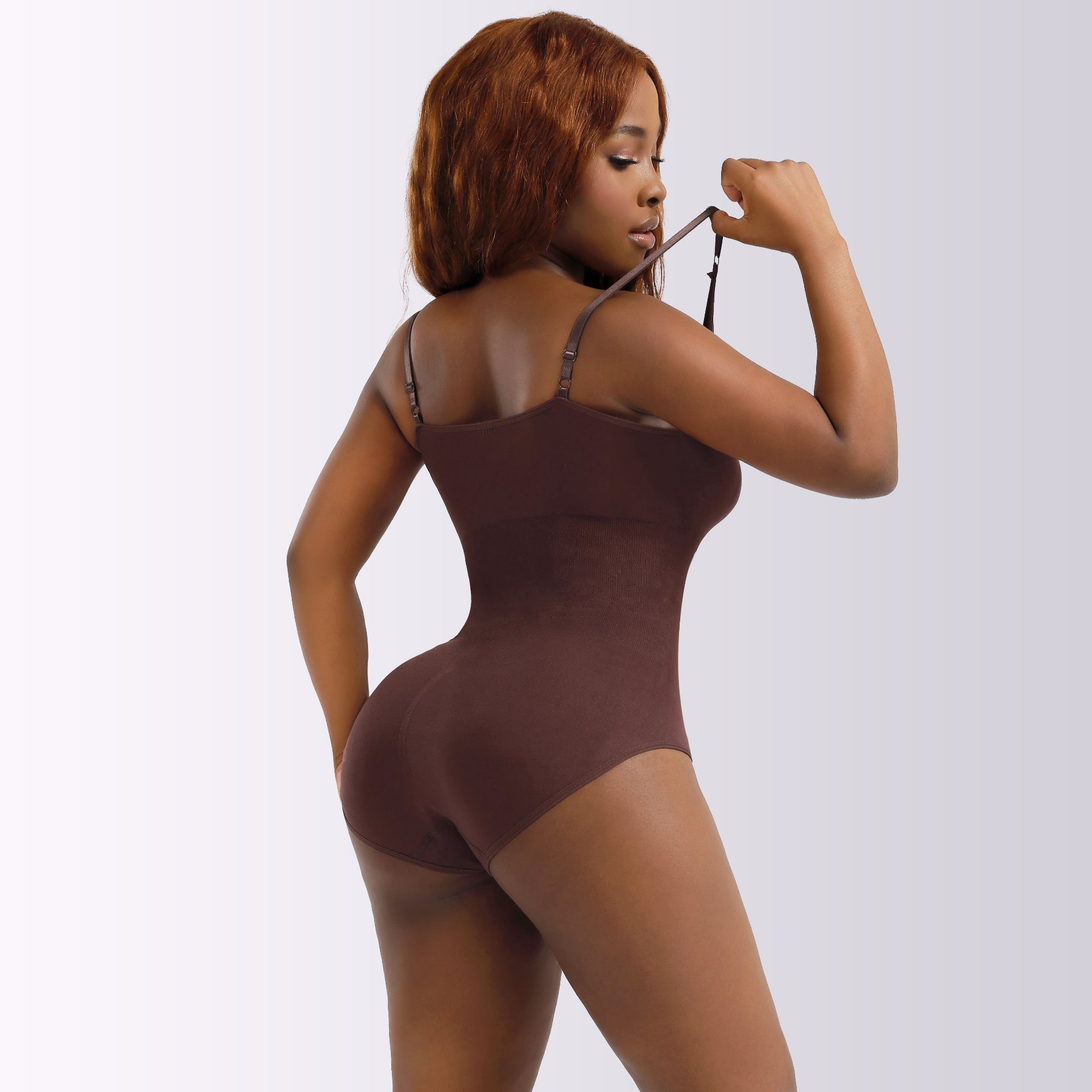 Woman wearing a brown bodysuit against a white background