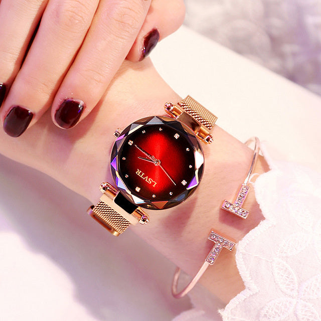 A woman's watch with a rose gold metal band and case, featuring a multicolored glass dial and a spiral crown.