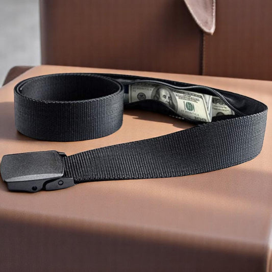 A black travel belt with a smooth square buckle, laid out on a brown surface, with some money partially visible in a hidden compartment.