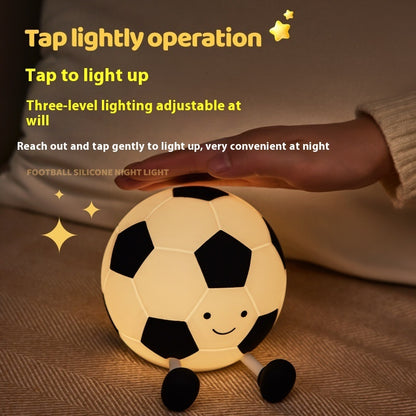 Soccer ball-shaped night light with tap-to-light feature on a brown surface.