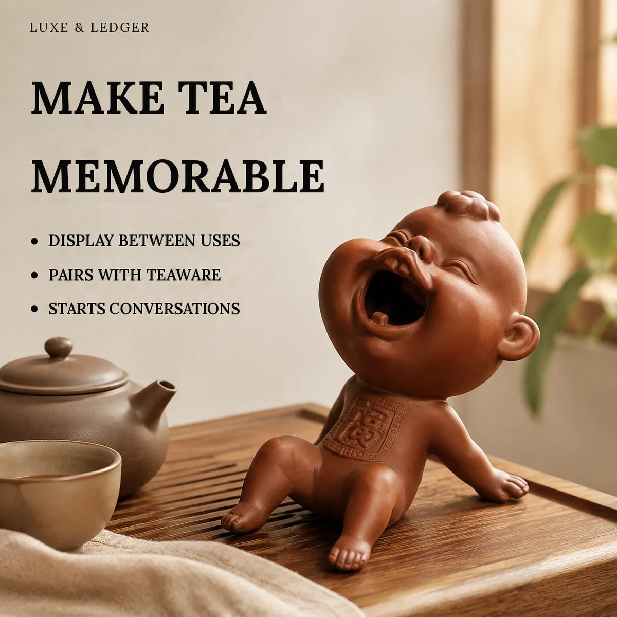 A ceramic laughing baby tea holder in a warm brown glaze, sitting on a wooden tea tray next to a matching teapot and cup. The image features promotional text on the left side reading 'MAKE TEA MEMORABLE' with bullet points, and the brand 'LUXE & LEDGER' at the top.