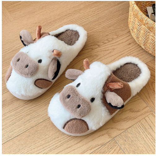 Pair of cow-themed slippers on a wooden floor