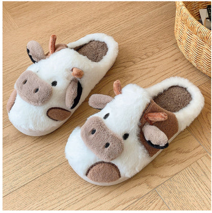 Pair of cow-themed slippers on a wooden floor