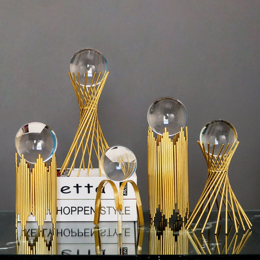 Decorative gold sculptures with glass spheres on a dark surface
