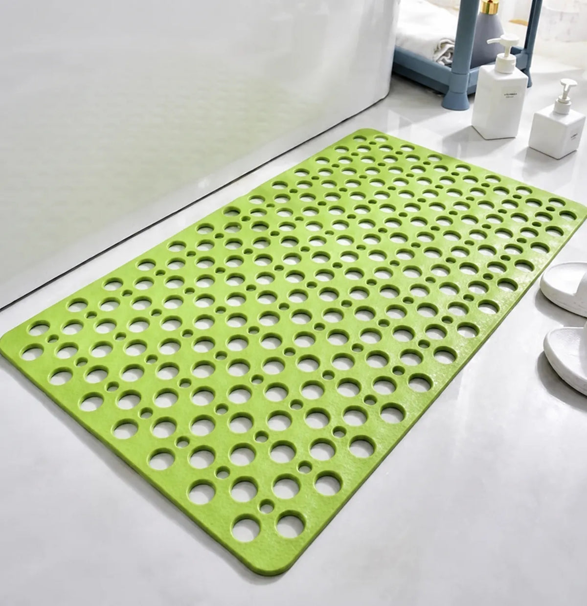 A bright lime green bath mat with a raised circular bubble pattern, shown on a white tiled bathroom floor next to a bathtub.