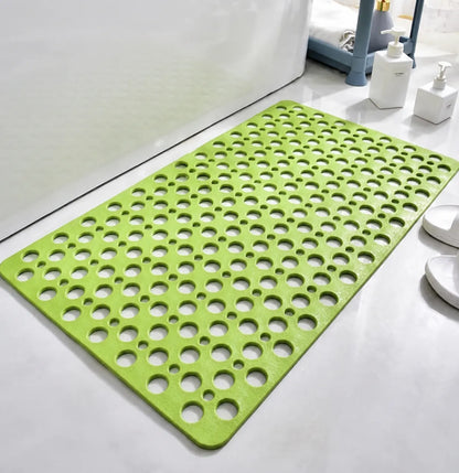 A bright lime green bath mat with a raised circular bubble pattern, shown on a white tiled bathroom floor next to a bathtub.