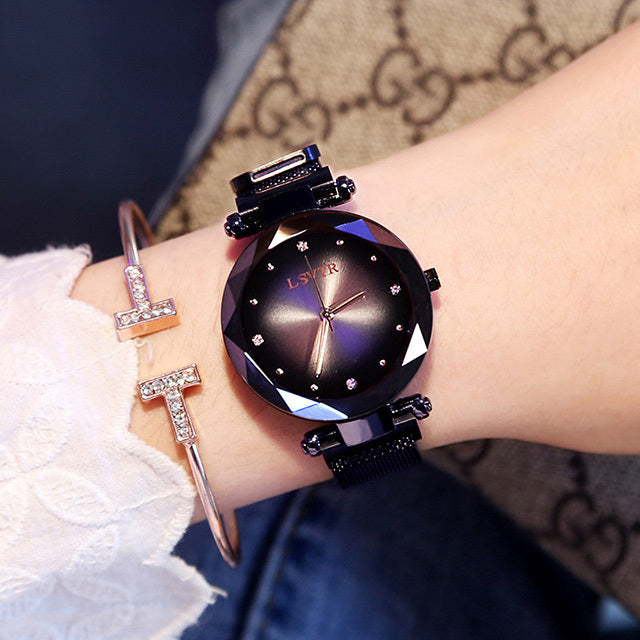 A woman's watch with a rose gold metal band and case, featuring a multicolored glass dial and a spiral crown.