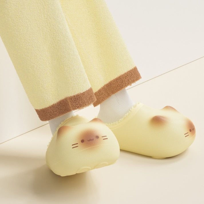 Yellow cartoon-style slippers worn with light-colored pants on a light floor.