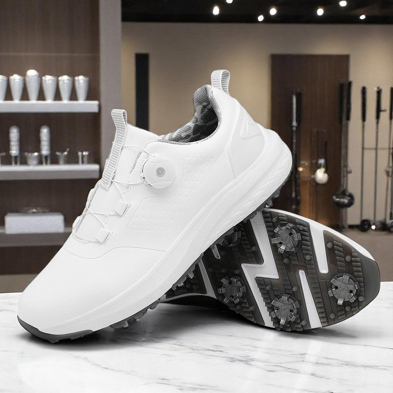 A pair of white golf shoes with a non-slip rubber sole, designed for all-terrain play on a green surface with golf balls and clubs in the background.