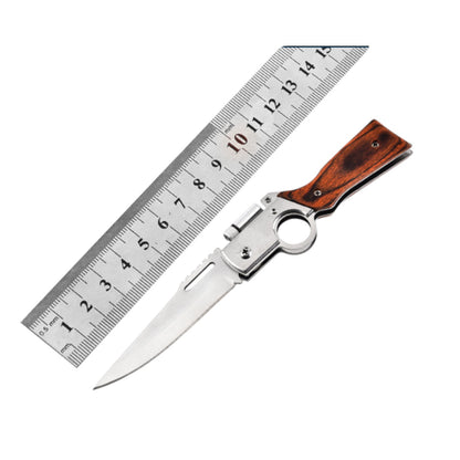 Folding knife with wooden handle next to a ruler on a white background