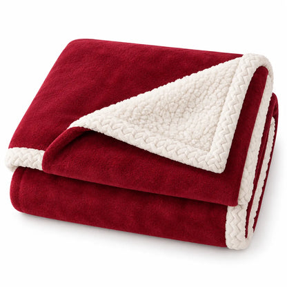 A folded fleece blanket with a deep red exterior and a cream sherpa lining, showing a braided border trim, set against a plain white background.