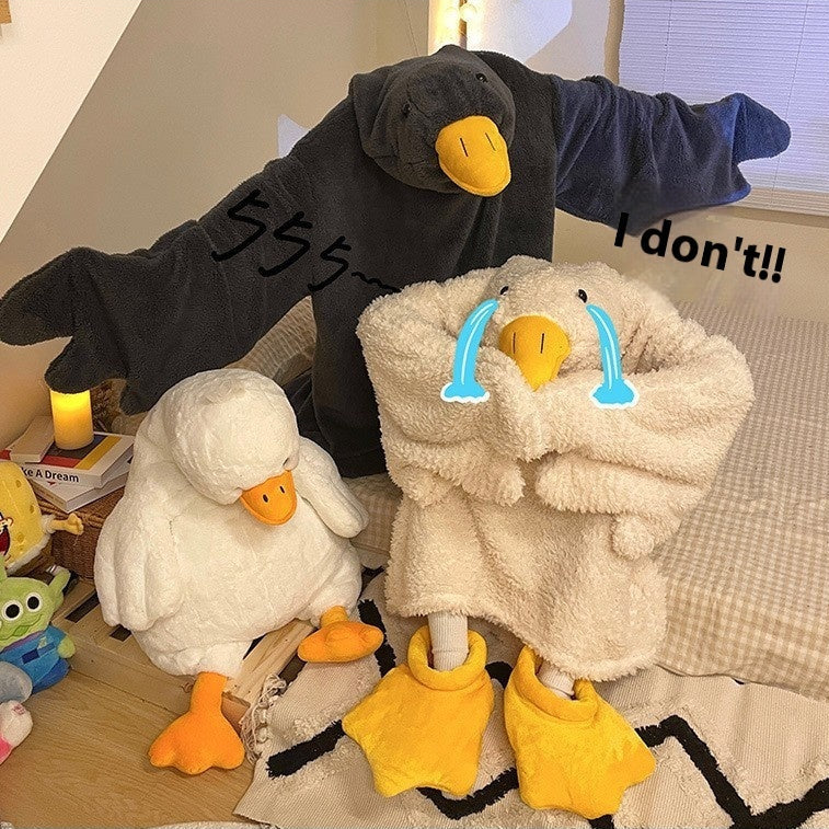 Two plush duck toys with text and water droplets on a bed.